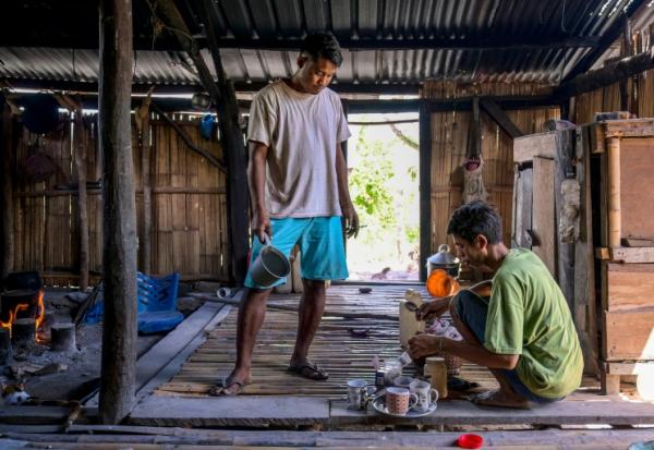 Le noble Umbu Ana Rara (g) regarde son esclave (d) Kanisius Kanyali Hambarita préparer des boissons au village de Tanggedu, dans l'est de l'île de Sumba, le 23 juin 2026 en Indonésie