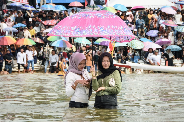 Des spectateurs lors d'une course nautique traditionnelle sur la rivière Kuantan, dans la province indonésienne de Riau, sur l'île de Sumatra, le 23 août 2025  