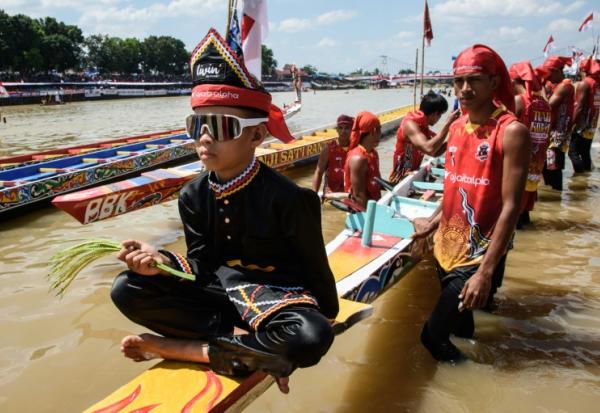 Rayyan Arkan Dikha assis à l'avant d'un bateau avant une course nautique traditionnelle, le 22 août 2025 sur la rivière Kuantan, dans la province indonésienne de Riau, sur l'île de Sumatra 