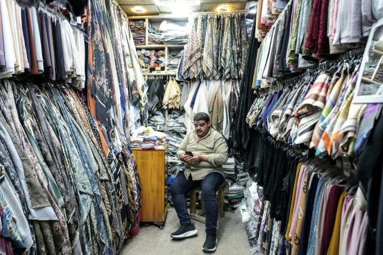 Un vendeur attend des clients dans sa boutique de vêtements de la vieille ville de Najaf, en Irak, le 22 avril 2026
