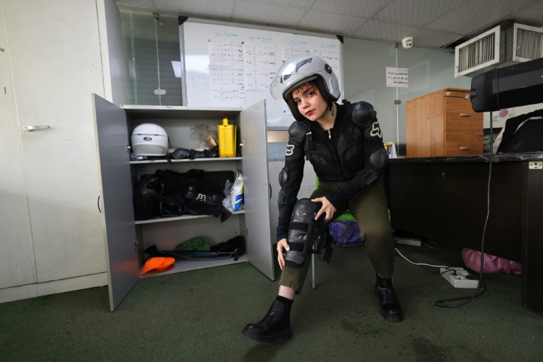 L'élève Narghes enfile des protège-tibias avant un cours de conduite de moto dans un centre d'entraînement du nord de Téhéran, le 7 décembre 2025 en Iran