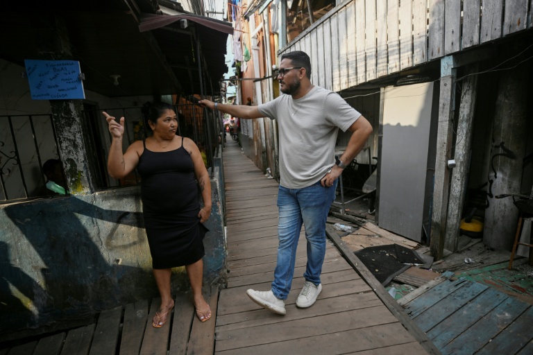 Gerson Bruno (d), président de l'association des résidents de Vila da Barca, parle avec une habitante de ce quartier pauvre bâti sur pilotis sur les rives du fleuve Guama à Belem, dans l'État du Para, le 5 novembre 2025 au Brésil