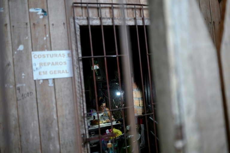 Une femme travaille devant sa machine à coudre chez elle à Vila da Barca, un quartier pauvre bâti sur pilotis sur les rives du fleuve Guama à Belem, dans l'État du Para, le 5 novembre 2025 au Brésil