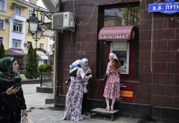 Des femmes se tiennent devant un distributeur de billets situé sur l'avenue Vladimir Poutine à Grozny, en Tchétchénie, le 26 juillet 2019