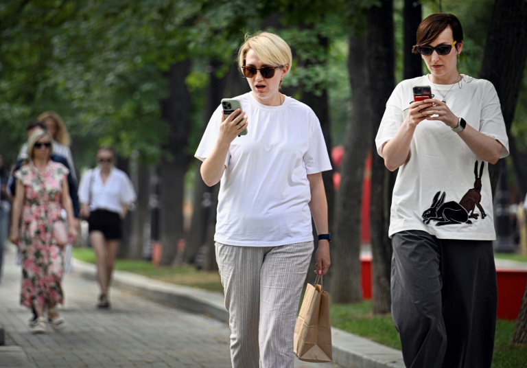 Des femmes utilisent leurs smartphones dans un parc à Moscou, le 30 juillet 2025