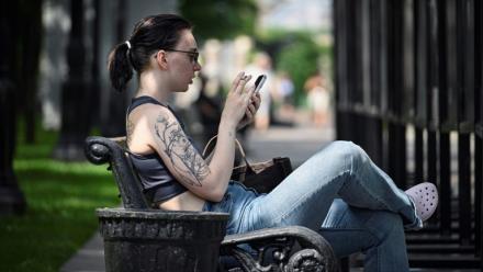 Une femme assise sur un banc utilise son smartphone à Moscou, le 30 juillet 2025