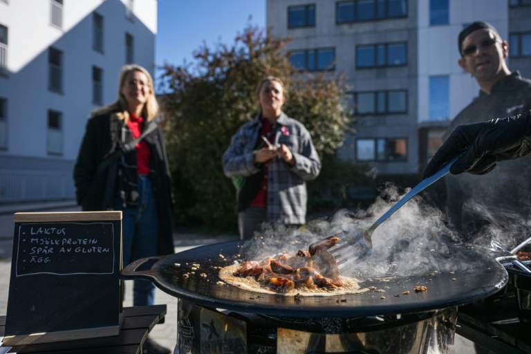 Des passants observent la préparation d'un plat à Hägersten, au sud de Stockholm, lors d'une initiative visant à sensibiliser aux repas qui peuvent être préparés dans des conditions d'état d'urgence, le 23 septembre 2025 en Suède