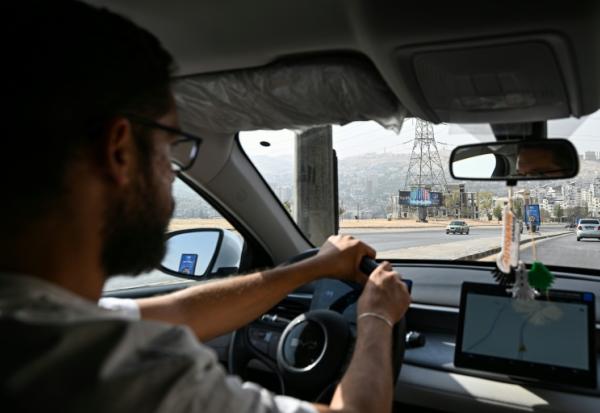 Ahmad al-Lahham, chauffeur pour l'une des principales applications de taxis "Yalla Go", au volant son véhicule hybride rechargeable à Damas, le 25 octobre 2026 en Syrie