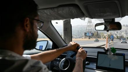 Ahmad al-Lahham, chauffeur pour l'une des principales applications de taxis "Yalla Go", au volant son véhicule hybride rechargeable à Damas, le 25 octobre 2026 en Syrie