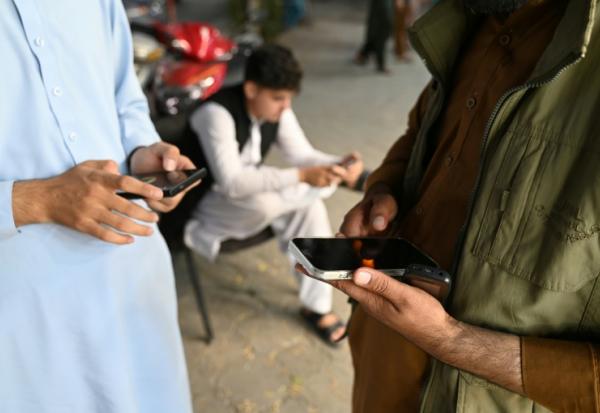 Des Afghans consultent leurs téléphones portables, le 1er octobre 2025 à Kaboul