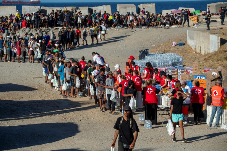 Des bénévoles de la Croix-Rouge distribuent de la nourriture aux migrants restés à Ceuta, sur une plage de l'enclave espagnole au Maroc, le 22 août 2026