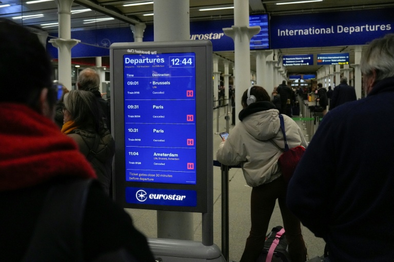 Des passagers regardent le tableau d'affichage montrant les trains annulés à la gare londonienne de St. Pancras après la suspension de toutes les liaisons Eurostar entre Paris et Londre le 30  décembre 2025