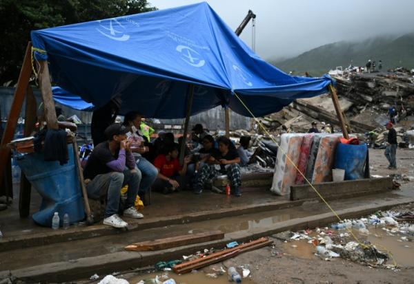 Des rescapés du double séisme s’abritent sous une bâche tandis que les secouristes fouillent les décombres des immeubles effondrés à Caraballeda, dans l’État de La Guaira, au Venezuela, le 11 juillet 2026