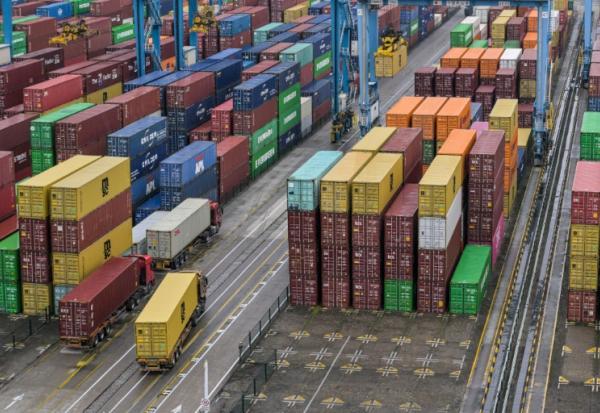 Des camions passent devant des conteneurs au port de Ningbo-Zhoushan, dans la province orientale du Zhejiang, le 28 mai 2025 en Chine