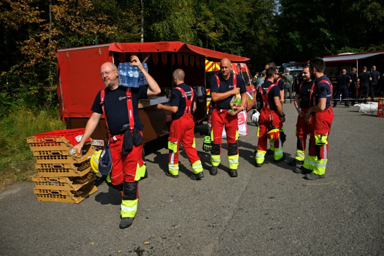 Des pompiers se servent en eau et en nourriture auprès d'un véhicule de soutien logistique des services d'incendie avant de partir lutter contre un feu dans le parc naturel des Hautes Fagnes, le 16 août 2026 à Eupen, dans l'est de la Belgique 