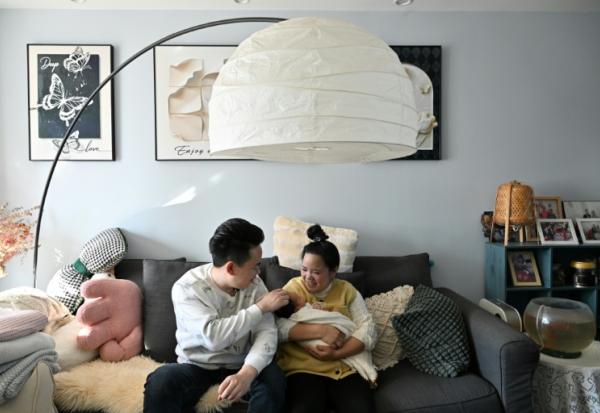 Zhang Xiaofei, 32 ans, et son époux Zhu Yunfei, 36 ans, avec leur fille de trois semaines dans leur appartement de Langfang, en périphérie de Pékin, le 6 mars 2026