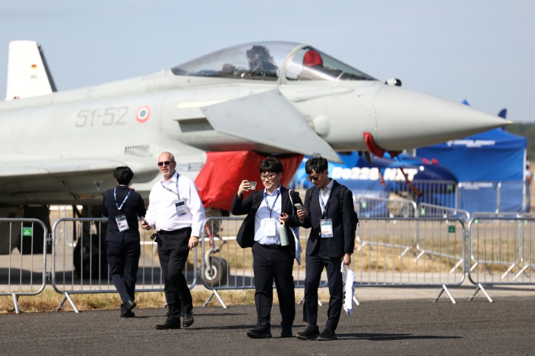Des délégués devant un Eurofighter Typhoon de l'armée de l'air italienne lors de la journée d'ouverture du salon aéronautique international de Farnborough, au sud-ouest de Londres, le 20 juillet 2026