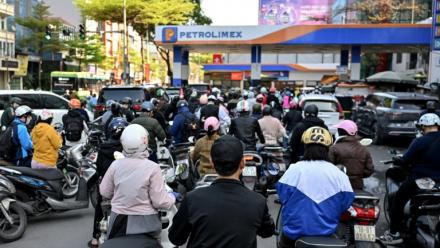 Des motocyclistes font la queue pour faire le plein d'essence dans une station-service à Hanoï, le 10 mars 2026 au Vietnam