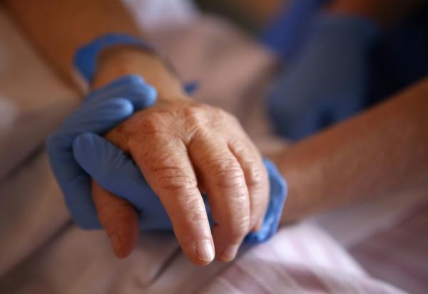 Un personnel soignant tient la main d'un patient en soins palliatifs, le 23 avril 2020 à l'hôpital Eugénie d'Ajaccio