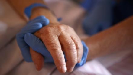 Un personnel soignant tient la main d'un patient en soins palliatifs, le 23 avril 2020 à l'hôpital Eugénie d'Ajaccio
