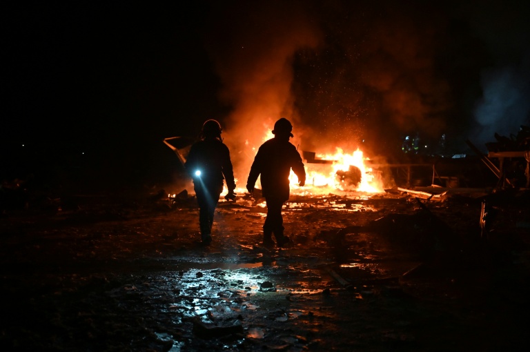 Des pompiers luttent contre un incendie provoqué par un bombardement russe sur un entrepôt de la compagnie des postes Nova Pochta dans un village près de Kharkiv, le 13 janvier 2026 en Ukraine