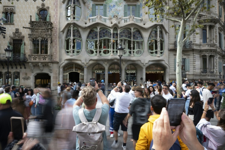 Des touristes devant la Casa Batllo, une création d'Antoni Gaudi, à Barcelone, le 11 octobre 2024, en Espagne