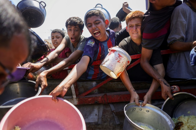 Des jeunes Palestiniens tentent d'obtenir du riz distribué par une cuisine caritative dans l'ouest de Gaza, le 28 août 2025