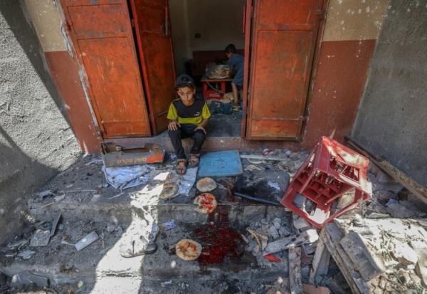 Des enfants palestiniens récupèrent du pain dans une boulangerie détruite par des frappes israéliennes dans le camp de réfugiés de Nousseirat, dans le centre de la bande de Gaza, le 8 mai 2025