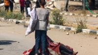 Une enfant palestinienne se tient devant le corps d'une personne tuée en venant chercher des vivres dans un site de distribution de la Fondation humanitaire de Gaza (GHF) soutenue par Israël et les Etats-Unis, dans le centre de la bande de Gaza, le 4 août 2025