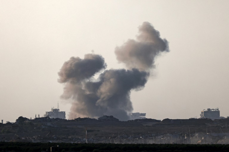 Photo prise depuis une position à la frontière entre Israël et la bande de Gaza montrant de la fumée au-dessus d'un secteur du territoire palestinien et des véhicules militaires après une frappe israélienne, le 20 août 2025