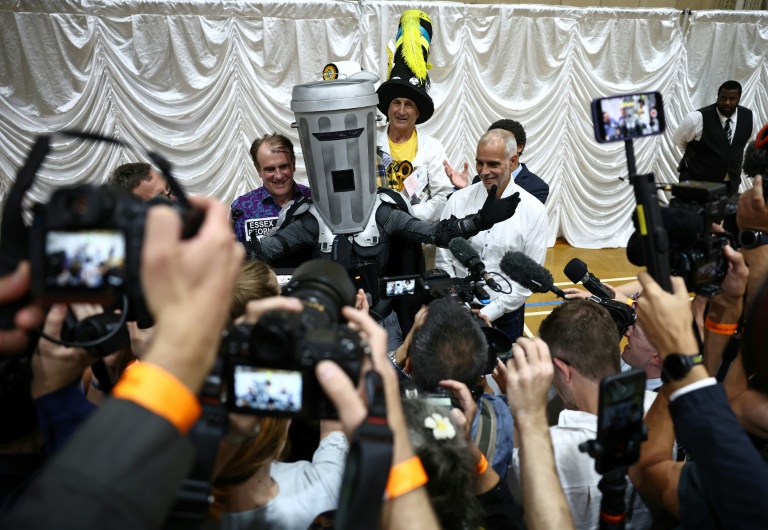 Le comte Tête-de-Poubelle (C) pose avec les autres candidats après la proclamation des résultats de l'élection partielle de Clacton au Clacton Leisure Centre, dans l'est de l'Angleterre, le 14 août 2026