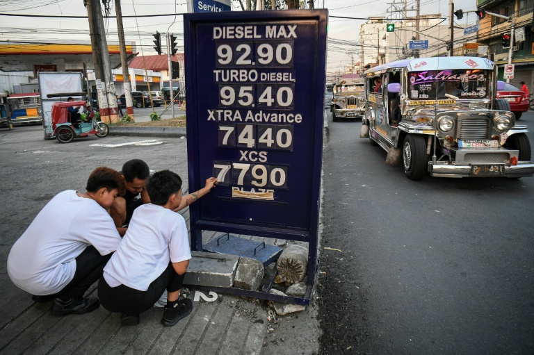 Des employés changent le prix des carburants dans une station-service de Manille, le 17 mars 2026 aux Philippines