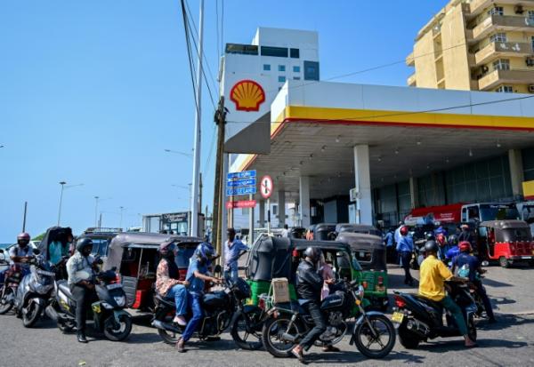 Des motoyclistes font la queue pour prendre du carburant à une station-service de Wellawatte, près de Colombo, le 16 mars 2026 au Sri Lanka 