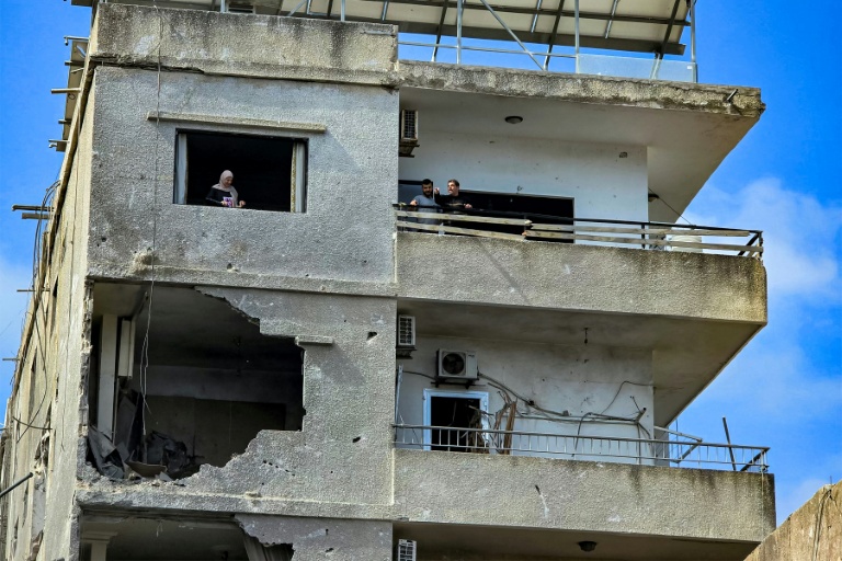 Des habitants dans un immeuble endommagé par une frappe israélienne octurne à Tyr, dans le sud du Liban, le 16 mai 2026