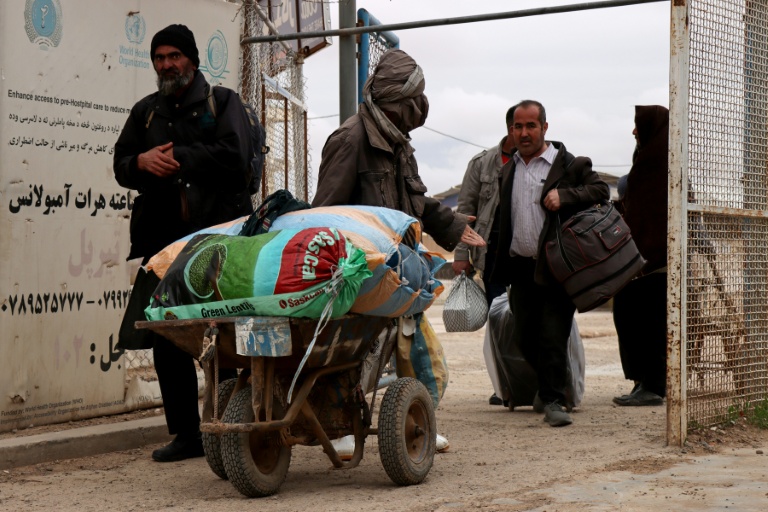 Des ressortissants afghans arrivent avec leurs effets personnels au poste-frontière d’Islam Qala, entre l’Afghanistan et l’Iran, dans la province de Herat Province, le 10 mars 2026, après leur arrivée en provenance d’Iran dans le contexte de la guerre au Moyen-Orient.