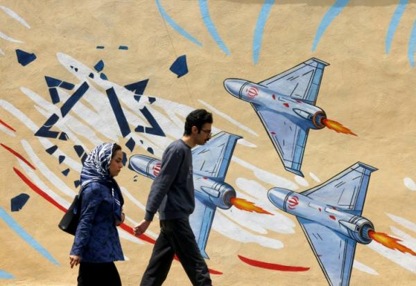 Un couple passe devant une peinture murale anti-américaine et anti-israélienne, à Téhéran, le 21 avril 2026