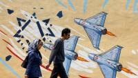 Un couple passe devant une peinture murale anti-américaine et anti-israélienne, à Téhéran, le 21 avril 2026
