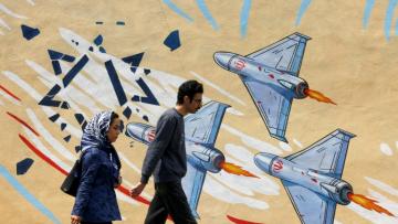 Un couple passe devant une peinture murale anti-américaine et anti-israélienne, à Téhéran, le 21 avril 2026