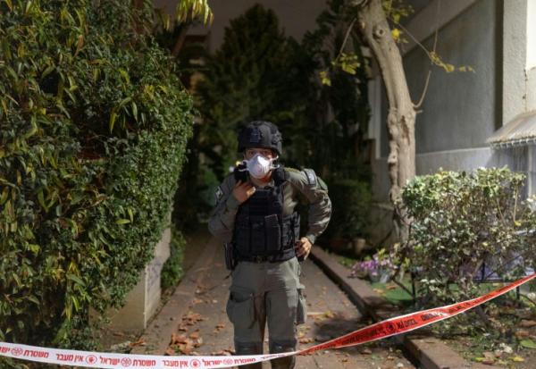 Un membre des forces de sécurité israéliennes devant une maison frappée par un projectile à Shoham, dans le centre d'Israël, le 13 mars 2026