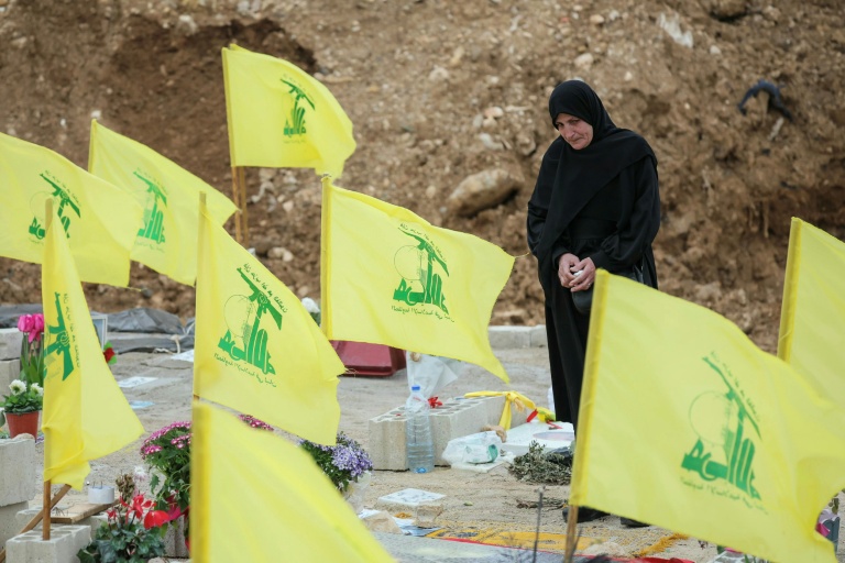 Une femme se recueille au milieu de drapeaux du Hezbollah dans la banlieue de Beyrouth, lors des funérailles le 29 mars 2026 des trois journalistes libanais tués la veille par une frappe israélienne
