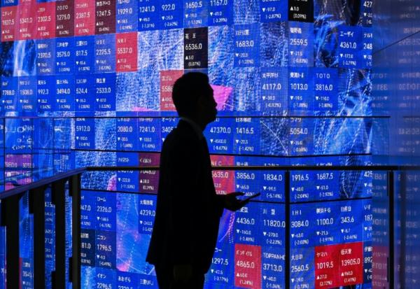 Une personne attend devant un panneau électronique à la Bourse de Tokyo, le 5 novembre 2025