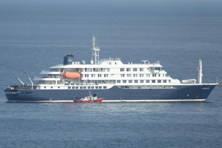 Un bateau-ambulance transportant des membres d'équipage en combinaisons de protection  retourne au port de Praia, après une visite à bord du bateau de croisière MV Hondius, au mouillage au large du port, le 5 mai 2026 au Cap-Vert
