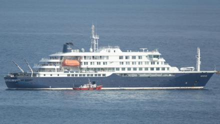 Un bateau-ambulance transportant des membres d'équipage en combinaisons de protection  retourne au port de Praia, après une visite à bord du bateau de croisière MV Hondius, au mouillage au large du port, le 5 mai 2026 au Cap-Vert
