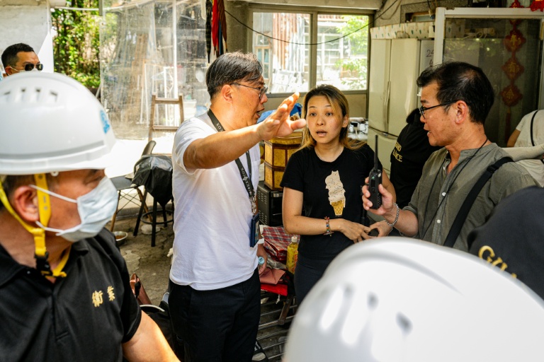 Un policier en civil demande à Niki So, une habitante d'un village de Kwu Tung, de quitter son domicile qui doit être démoli pour faire place à un vaste projet de pôle technologique, le 23 juin 2026 dans les Nouveaux Territoires à Hong Kong