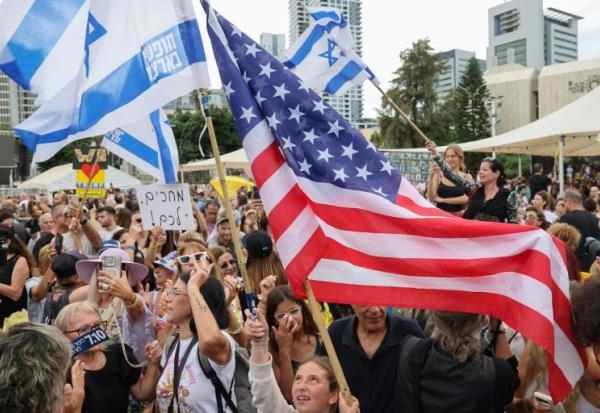 Des personnes agitent des drapeaux israéliens et américains sur la place des otages à Tel-Aviv le 9 octobre, après l'annonce d'un accord entre Israël et le Hamas