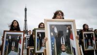 Des militants de l'association Action non violente - Cop21 (ANV-Cop21) tiennent des portraits à l'envers du président Emmanuel Macron décrochés dans différentes mairies, le 8 décembre 2019 sur l'esplanade du Trocadéro, à Paris