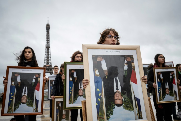 Des militants de l'association Action non violente - Cop21 (ANV-Cop21) tiennent des portraits à l'envers du président Emmanuel Macron décrochés dans différentes mairies, le 8 décembre 2019 sur l'esplanade du Trocadéro, à Paris