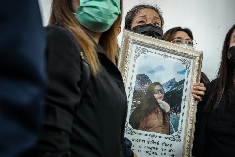 Une proche tient un portrait d'une des victimes de l'incendie dans un bar, le 14 juillet 2026 à l'hôpital général de la police de Bangkok  en Thaïlande