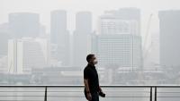 Un passant porte un masque de protection le long du boulevard à Marina Bay, noyé dans la brume, le 12 octobre 2026 à Singapour 