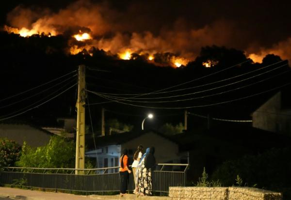 Des habitants observent les flammes sur les crêtes des collines tandis que les pompiers luttent contre un incendie de forêt dans la région de Cebreros, près d’Ávila, à 80 km à l’ouest de Madrid, dans la nuit du 24 juillet 2026